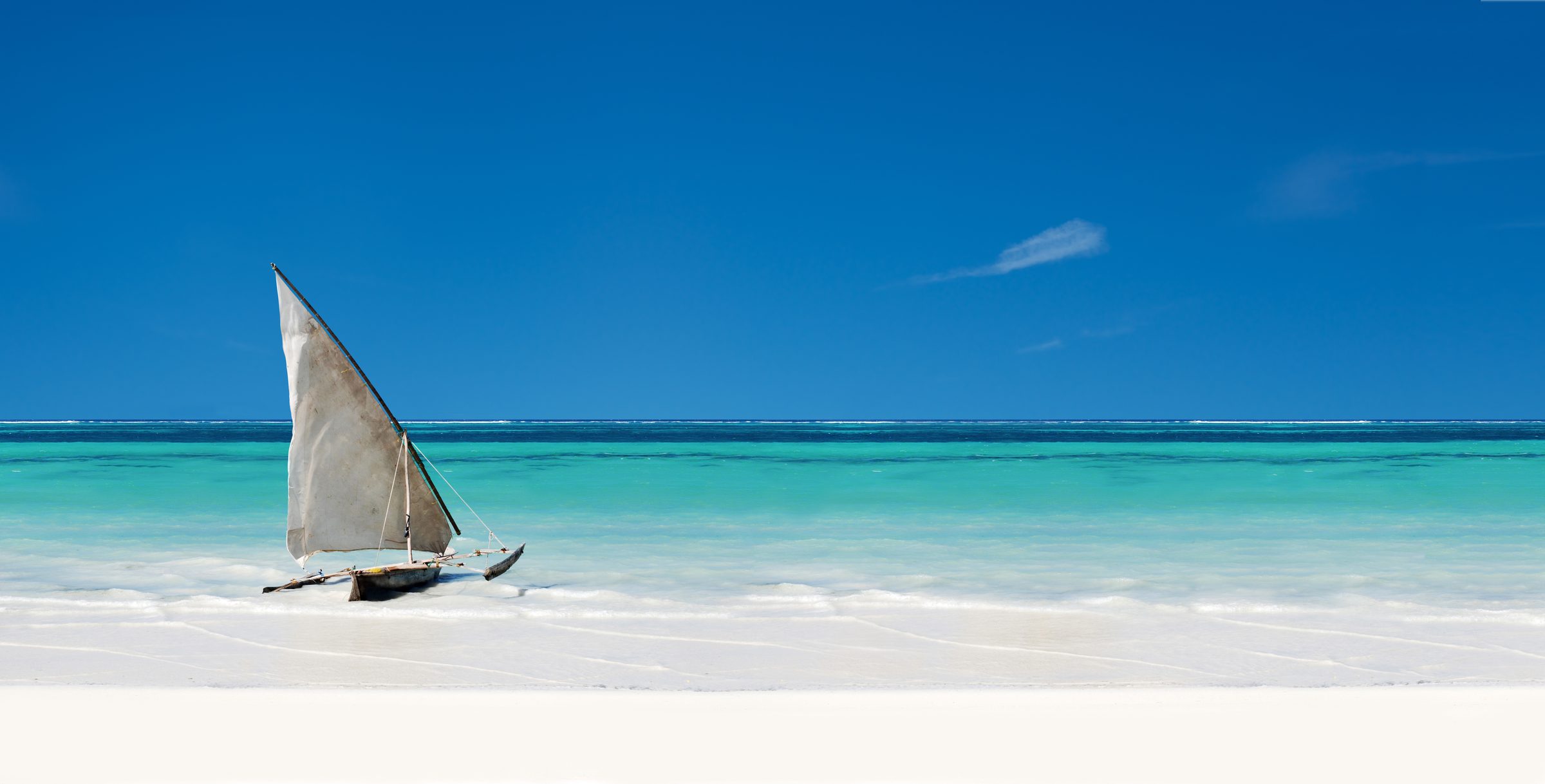Zanzibar — traditional dhow on white sand, Indian Ocean